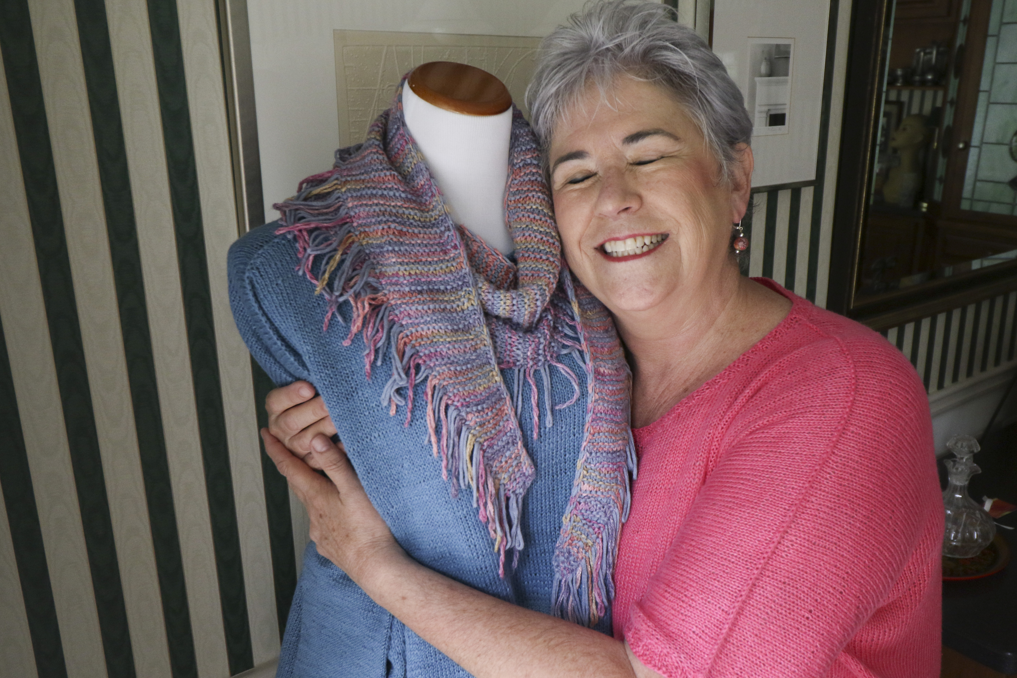 Staff Photo by Dan Henry. Nancy Hall dresses a figure form with items that she has knitted before taking photos of them to post to her MyParadeDesigns storefront on Etsy.