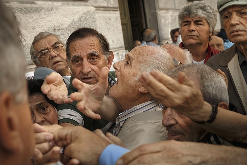 Pensioners try to get a number to enter inside a bank in Athens, Wednesday, July 1, 2015. About 1,000 bank branches around the country were ordered by the government to reopen Wednesday to help desperate pensioners without ATM cards cash up to 120 euros ($134) from their retirement checks. 