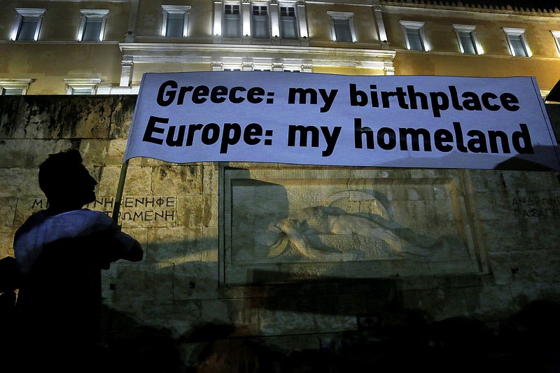 
              A demonstrator holds a banner during a rally organized by supporters of the YES vote for the upcoming referendum in front of the Greek Parliament in Athens, Tuesday, June 30, 2015. Greece's European creditors were assessing a last-minute proposal Athens made for a new two-year rescue deal, submitted just hours before the country's international bailout program expires and it loses access to billions of euros in funds. (AP Photo/Petros Karadjias)
            
