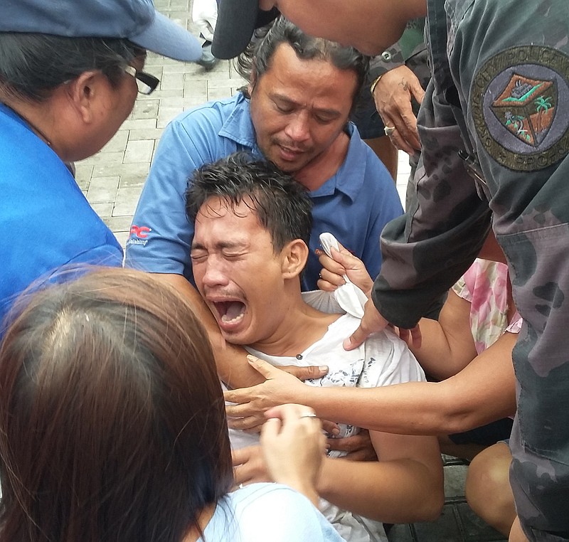 
              Police and rescuers comfort a crying passenger after he was brought ashore from a capsized passenger ferry Thursday, July 2, 2015, in Ormoc city, central Philippines. Coast Guard officials say the boat capsized minutes as it left a central Philippine port in choppy waters, leaving dozens dead and many missing.(AP Photo/John Pilapil)
            