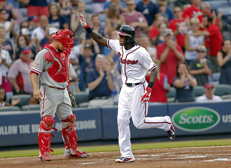 Atlanta Braves' Cameron Maybin, right, gestures as he runs past Philadelphia Phillies catcher Cameron Rupp to score after hitting a solo home run in their game Saturday, July 4, 2015, in Atlanta. 