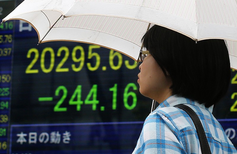 
              A woman walks past an electronic stock indicator of a securities firm in Tokyo, Monday, July 6, 2015.  Greece's foray into the unknown with its rejection of terms set by its international creditors is jolting markets as investors react to looming uncertainties. (AP Photo/Shizuo Kambayashi)
            