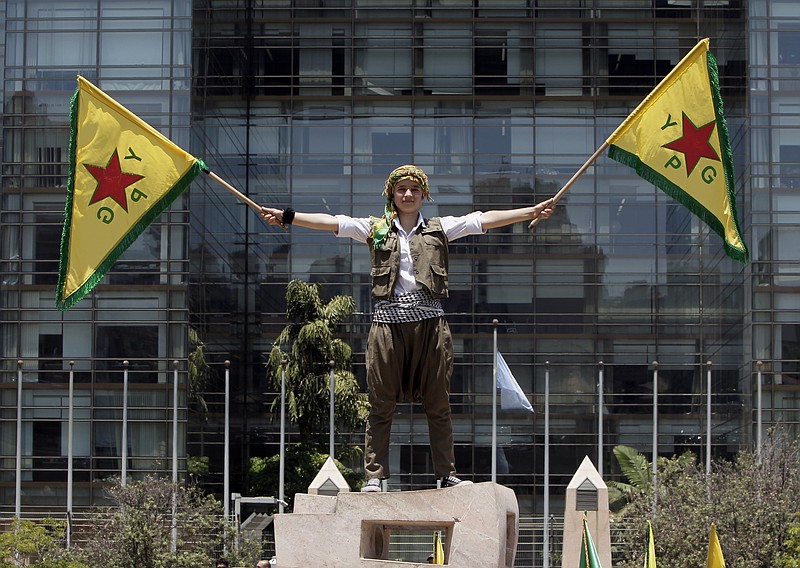 A Kurdish girl who lives in Lebanon waves flags of the Kurdish People's Protection Units, also known as YPG, during a demonstration in solidarity with their Kurdish brethren in northern Syria who are fighting against Islamic State group militants, in front of the United Nations headquarters in Beirut, Lebanon, Sunday, July 5, 2015.