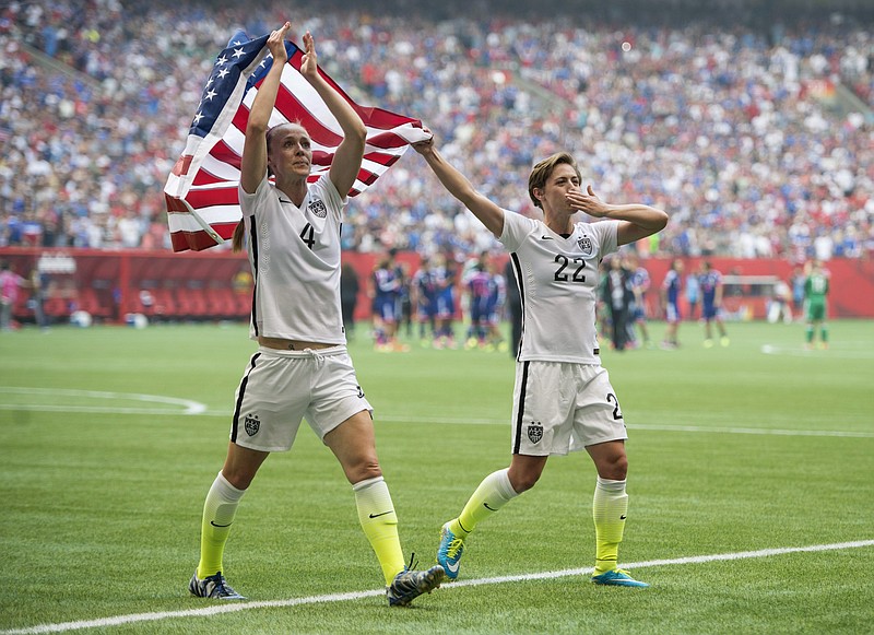 USA teammates Becky Sauerbrunn, left, and Meghan Klingenberg celebrate following their win over Japan at the FIFA Women's World Cup soccer championship in Vancouver, British Columbia, Canada, Sunday, July 5, 2015. (Jonathan Hayward/The Canadian Press via AP) MANDATORY CREDIT