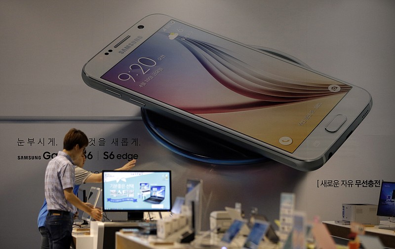 
              Employees of Samsung Electronics Co. check the products near an advertisement of Samsung Electronics' Galaxy S6 smartphone at a Samsung Electronics shop in Seoul, South Korea, Tuesday, July 7, 2015. Samsung Electronics Co. forecast lower-than-expected profit for the April-June quarter in a sign that its much-anticipated Galaxy S6 smartphones failed to lead a meaningful recovery.(AP Photo/Lee Jin-man)
            