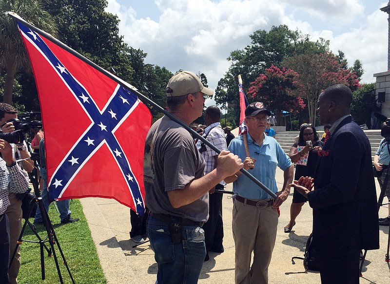 Randy Saxon, left and Wayne Whitfield, both of Anderson, S.C., discuss the Confederate flag on the South Carolina Statehouse grounds with Brodrick S. Hall of Atlanta, right, on Monday, July 6, 2015.