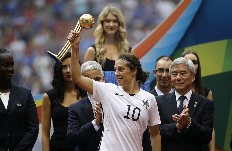 United States' Carli Lloyd holds the Golden Ball trophy for being the tournament MVP as she stands with tournaments officials after the team beat Japan in the FIFA Women's World Cup soccer championship in Vancouver, British Columbia, Canada, Sunday, July 5, 2015.