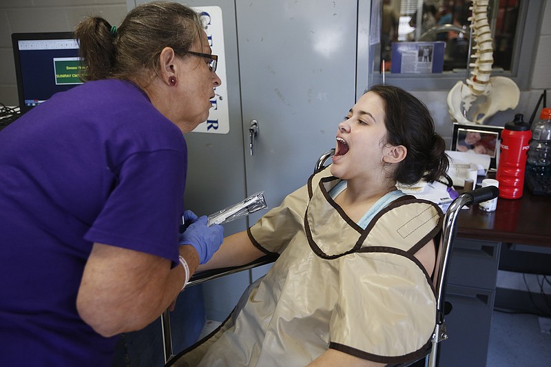 Elizabeth Larwood, left, prepares to take a dental X-ray of Iricelys Irizarry's wisdom tooth during a Sept. 20, 2014, clinic provided by Remote Area Medical at Ooltewah High School in Ooltewah, Tenn. Another clinic will be held this weekend in Cleveland.