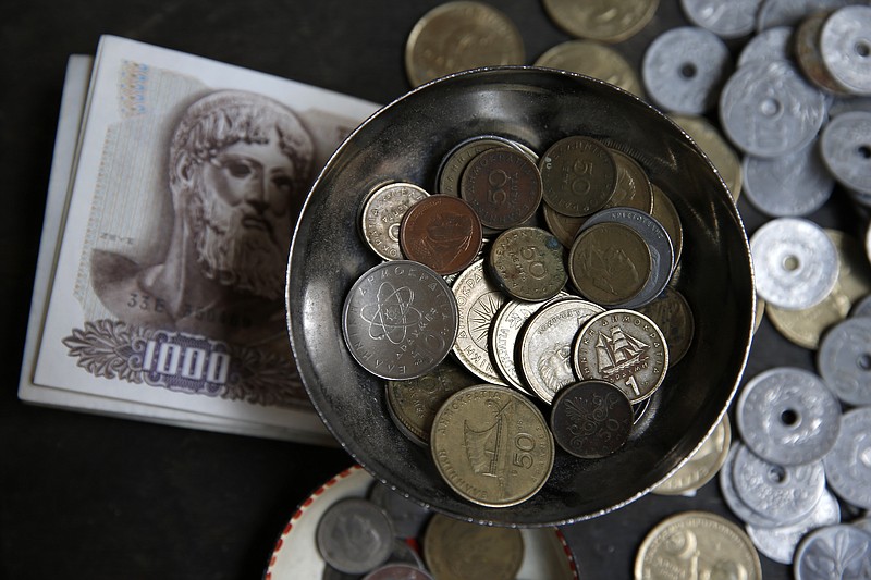 Drachma notes and coins, Greece's national currency before adopting the Euro, are displayed for sale at a street market in Athens in this June 3, 2015, file photo. Even in the digital age, it would take months to create and distribute coins and bank notes if Greece abandons the euro and restores its old currency. 
            