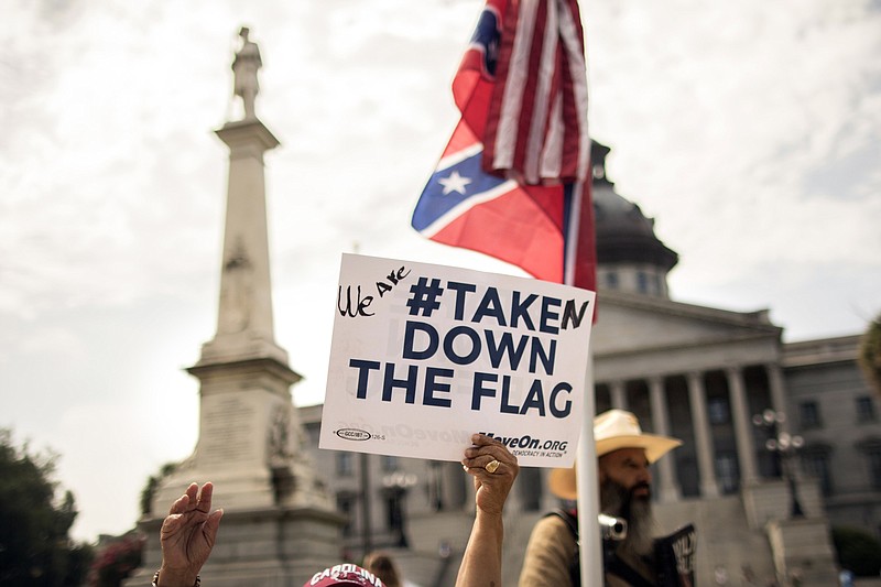Maria Calef holds a sign in front of the Confederate monument outside the South Carolina State House in Columbia after the state House voted to remove the Confederate battle flag from the grounds of the State Capitol on Thursday.(Stephen B. Morton/The New York Times)