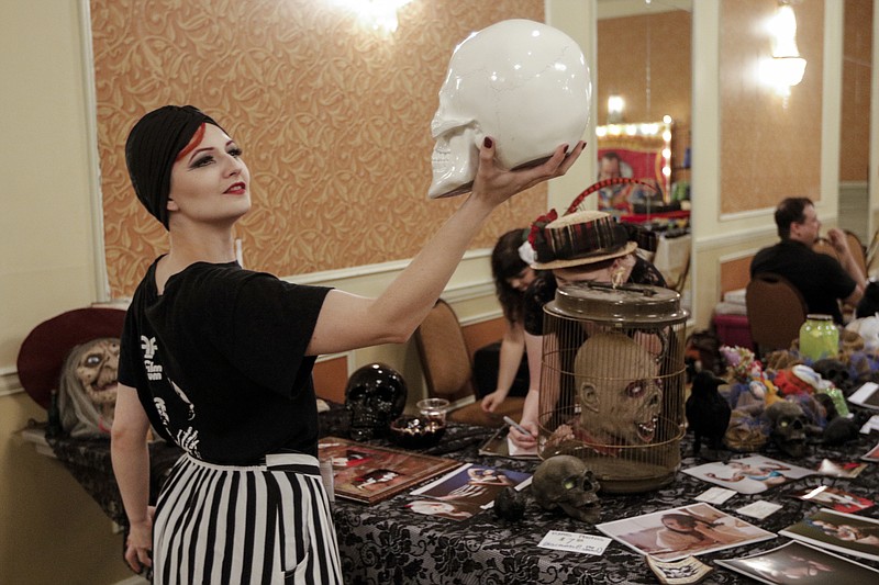 Trini Quinn picks up a porcelain skull from a display at the Shuddercon horror and sci-fi convention Saturday, July 11, 2015, at the Chattanooga Choo Choo in Chattanooga, Tenn.