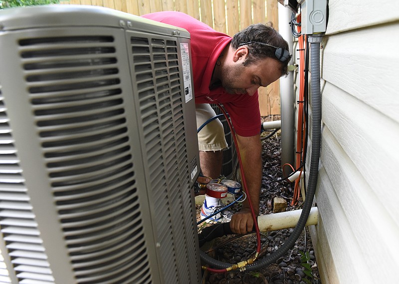 B. J. Harjes (CQ) of American Air works with a crew to install an new air conditioning unit on Thursday, July 8, 2015, in Ringgold, Ga. Summer is the busiest season for the air conditioning business. 