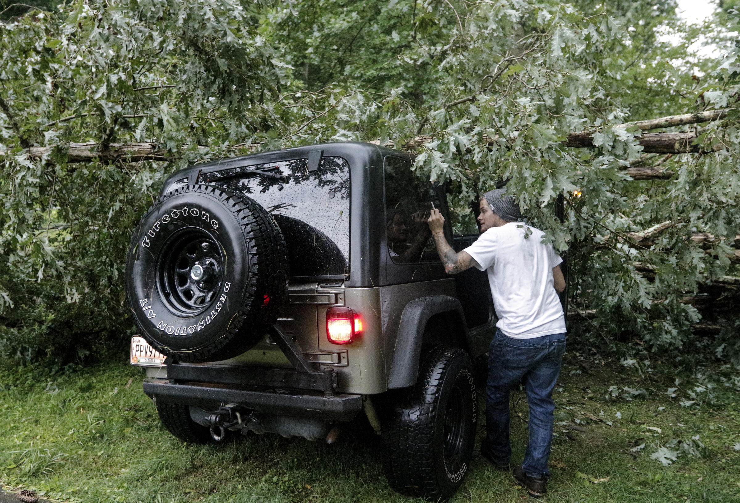 Gage Hahn checks the rear of his jeep which was hit by a downed tree in the yard of his home on Hedgewood Drive after heavy thunderstorms swept through the region Tuesday, July 14, 2015, in Red Bank, Tenn.