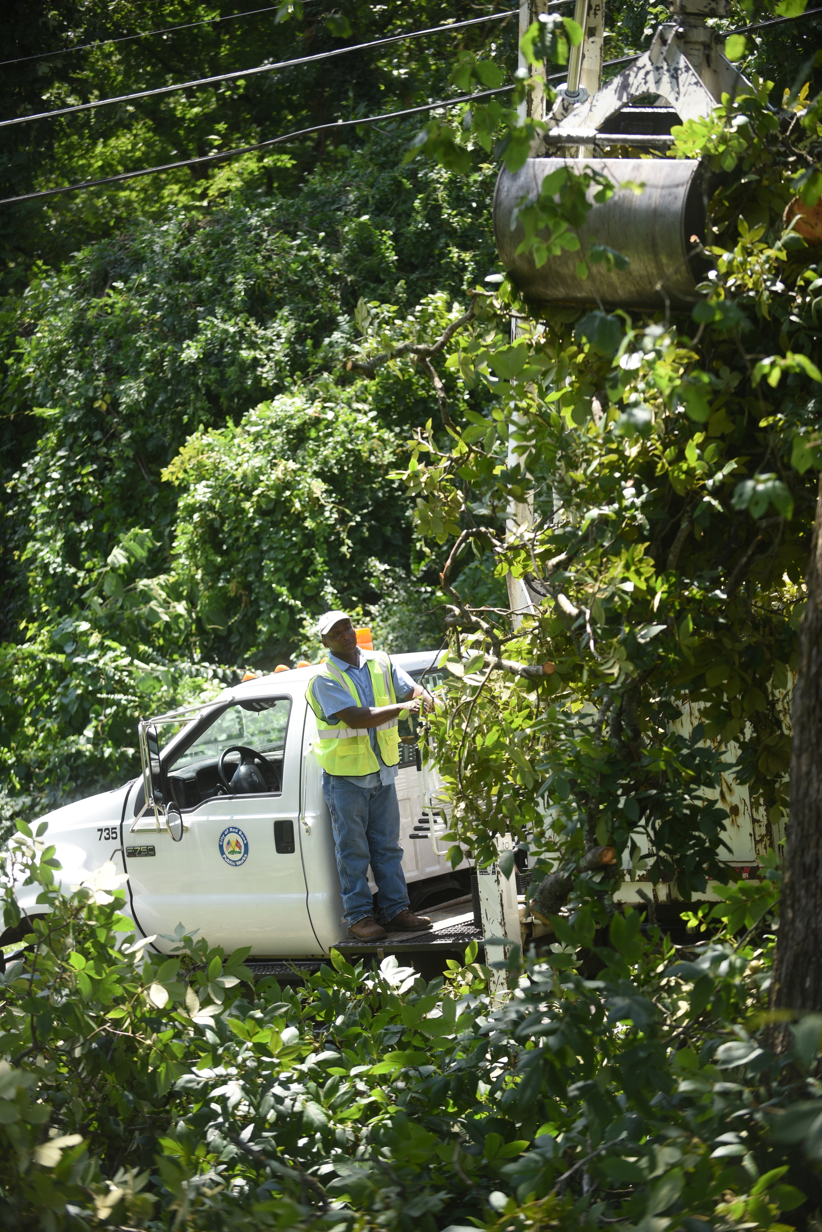 Scott Bradley, with Red Bank Public Works, picks up brush on Lynda Drive in Red Bank Wednesday, July 15, 2015 after storms came through the area Tuesday.