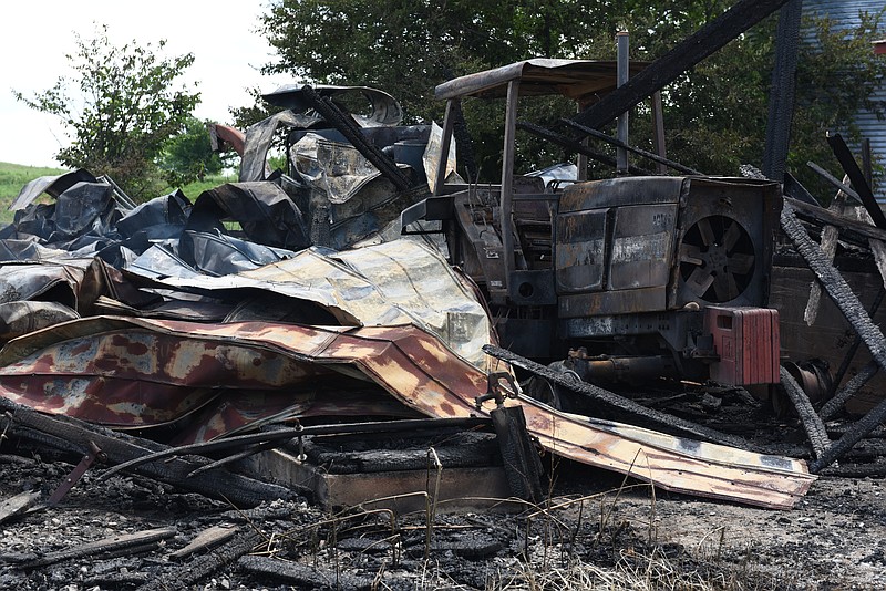 A destroyed tractor and other farm equipment is seen in the remains of an old barn on Jim Hagler's property on Wednesday, July 15, 2015, at Hagler Farms in Ten Mile, Tenn. The barn caught fire Tuesday night and burned to the ground after an apparent lightning strike during strong thunderstorms that moved through the area.