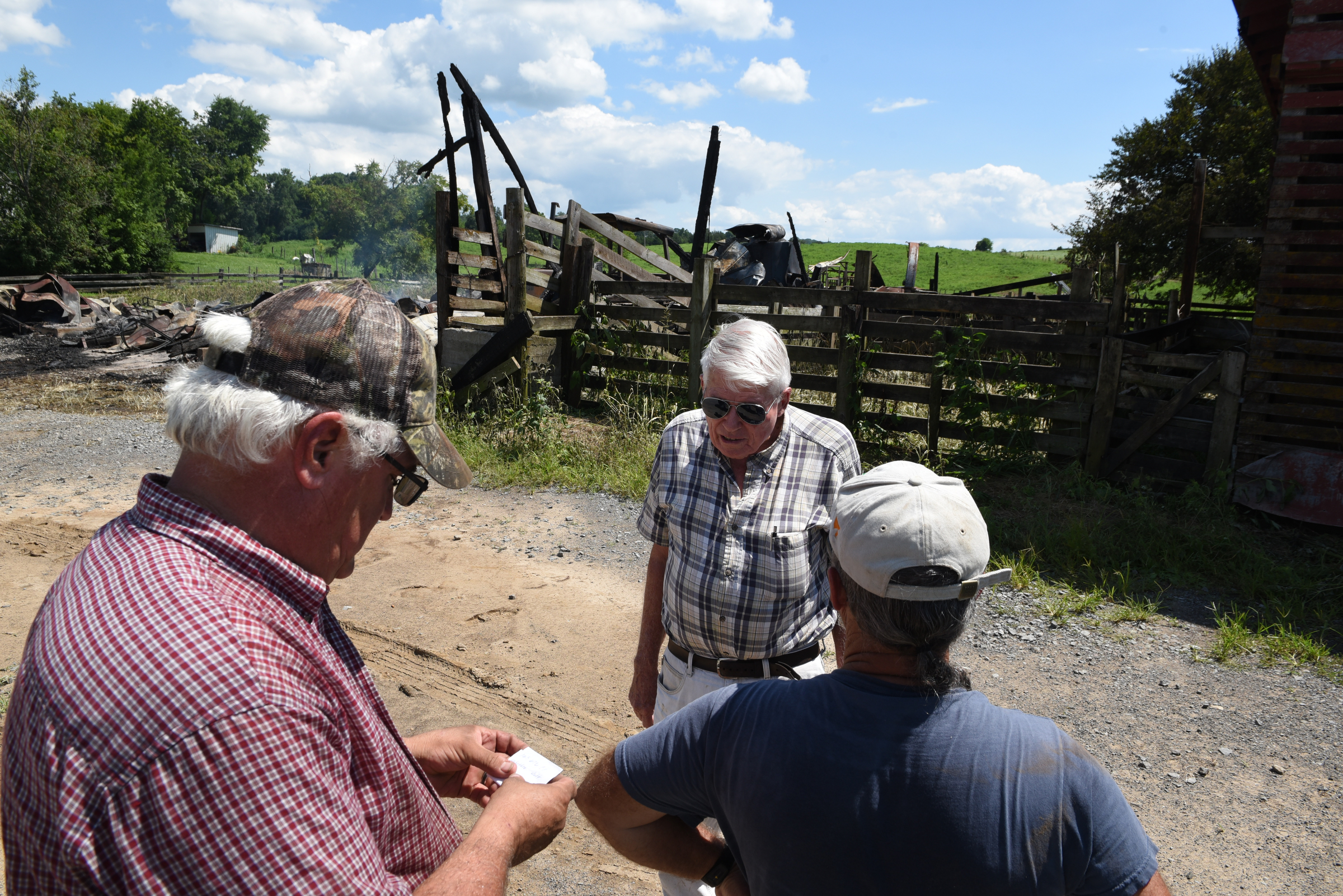 Jim Hagler, center, talks with Joe Cardwell, left, and Darrell Wyrick in front of the remains of an old barn on his property on Wednesday, July 15, 2015, at Hagler Farms in Ten Mile, Tenn. The barn caught fire Tuesday night and burned to the ground after an apparent lightning strike during strong thunderstorms that moved through the area.