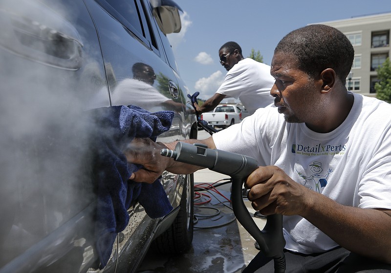 Detail Xperts technicians Fred Robinson, right, and Thaddeus Hayes, III, demonstrate how they clean a vehicle with a steamer Wednesday, July 15, 2015, in the parking lot of the SBC INCubator in Chattanooga, Tenn. Detail XPerts offers eco-friendly vehicle cleaning and says they can clean entire semi-trailer with about 5 gallons of water.