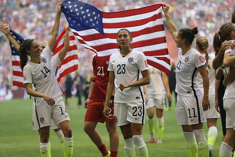 United States' Morgan Brian (14), Christen Press (23), and Ali Krieger (11), celebrate with the U.S. flag after the U.S. beat Japan 5-2 in the FIFA Women's World Cup soccer championship in Vancouver, British Columbia, Canada, on July 5, 2015.