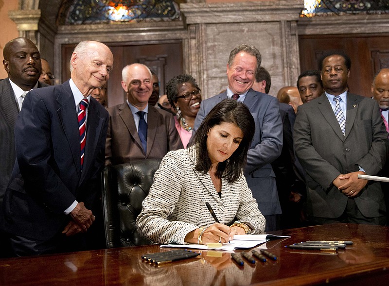 
              South Carolina Gov. Nikki Haley signs a bill into law as former South Carolina governors and officials look on Thursday, July 9, 2015, at the Statehouse in Columbia, S.C. The law enables the removal of the Confederate flag from the Statehouse grounds more than 50 years after the rebel banner was raised to protest the civil rights movement. (AP Photo/John Bazemore)
            