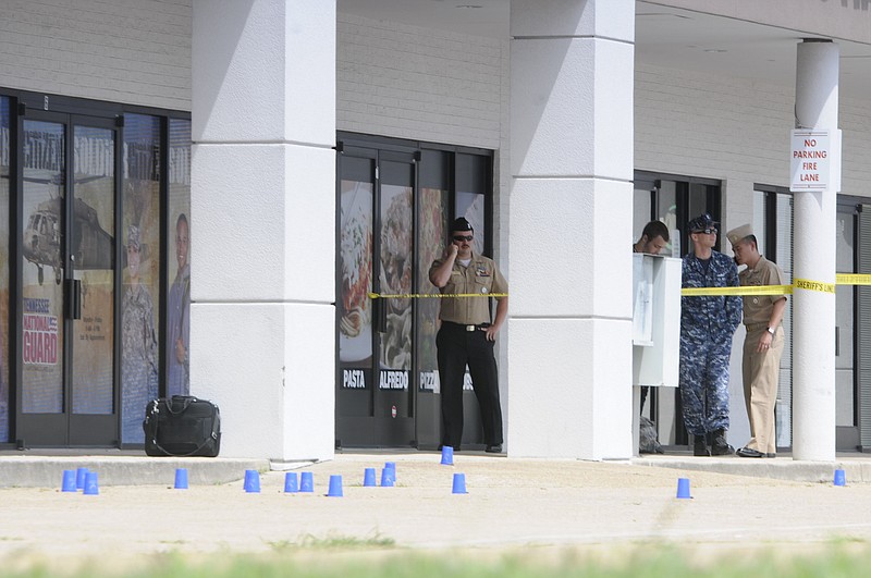 Army Recruitment personnel stand outside the Recruitment Center on Lee Highway. Blue evidence markers show shell casings in the parking lot.