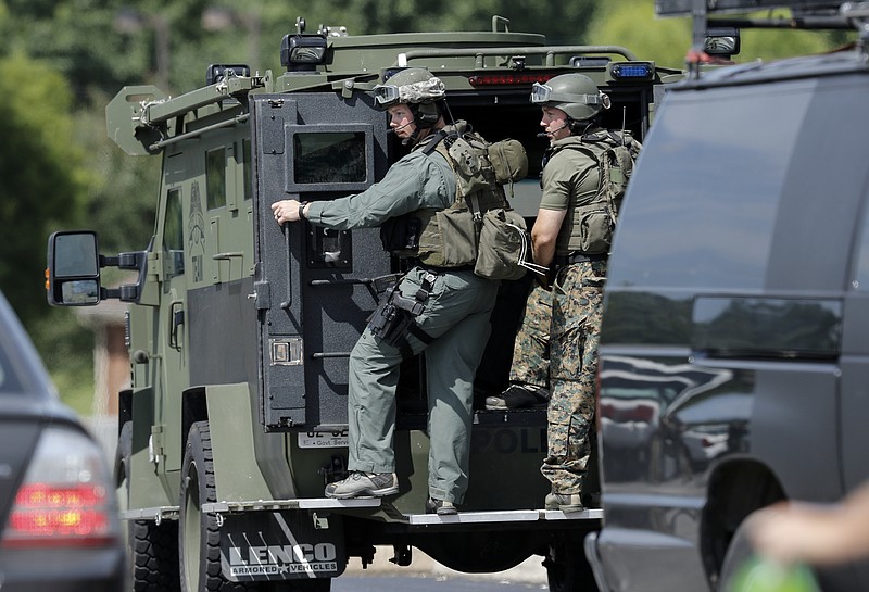 Law enforcement perch on the rear of an armored vehicle as they prepare at a staging area on Hixson Pike to investigate the nearby home of gunman Mohammad Abdulazeez on Thursday, July 16, 2015, in Chattanooga
