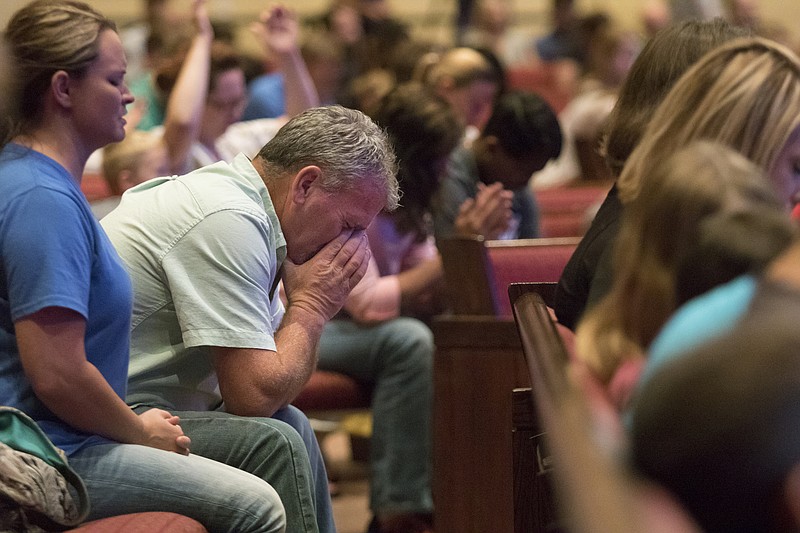 Corey Groce puts his face in his hands as he prays during a prayer vigil at Redemption Point Church on Thursday. The vigil followed shootings at both the Lee Highway Armed Forces Recruiting Center and the Naval and Marine Reserve Center on Amnicola Highway. The attack left five dead, including the shooter. Three others were wounded, including a Chattanooga police officer.