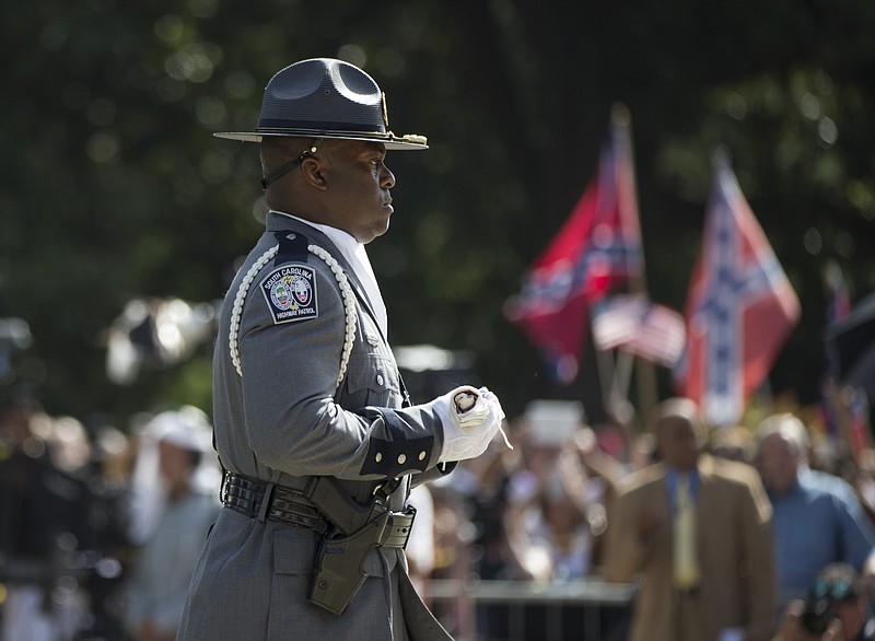 A member of an honor guard from the South Carolina Highway patrol carries a Confederate battle flag as they remove it from the Capitol grounds Friday, July 10, 2015, in Columbia, S.C. The Confederate flag was lowered from the grounds of the South Carolina Statehouse to the cheers of thousands on Friday, ending its 54-year presence there and marking a stunning political reversal in a state where many thought the rebel banner would fly indefinitely. (AP Photo/John Bazemore)