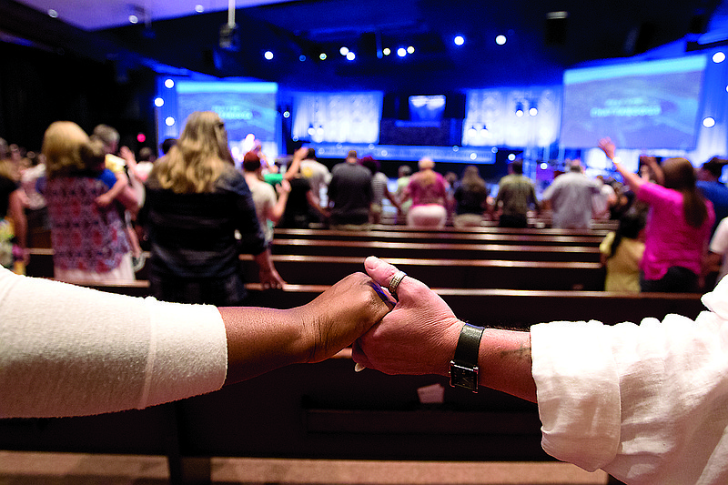 People hold hands during a prayer vigil at Redemption Point Church on Thursday, July 16, 2015, in Chattanooga, Tenn. The vigil followed a shooting at both the Lee Highway Armed Forces Career Center and the Naval Operational Support Center on Amnicola Highway which left five dead, including the shooter, and a Chattanooga police officer wounded.