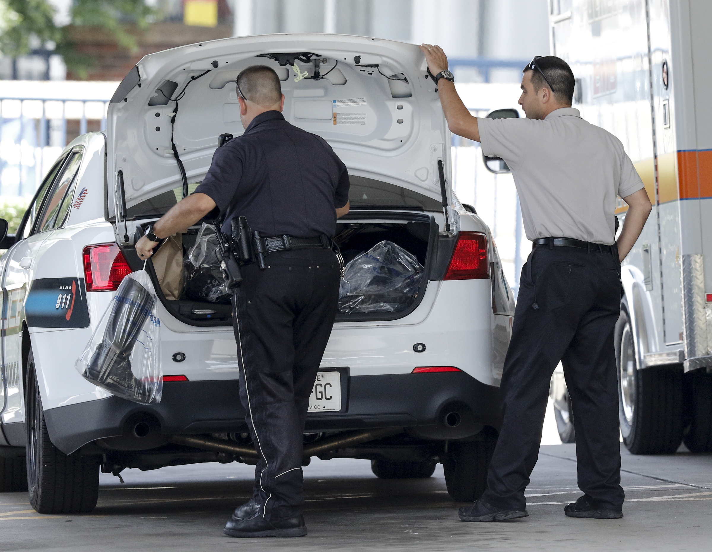 Officers put plastic bags of items into the trunk of a patrol car in the ambulance bay of Erlanger Hospital's ER after a shooting at both the Lee Highway Armed Forces Career Center and the Naval Operational Support Center on Amnicola Highway on Thursday, July 16, 2015, in Chattanooga, Tenn. The shooting left five dead, including the shooter, and a Chattanooga police officer wounded.