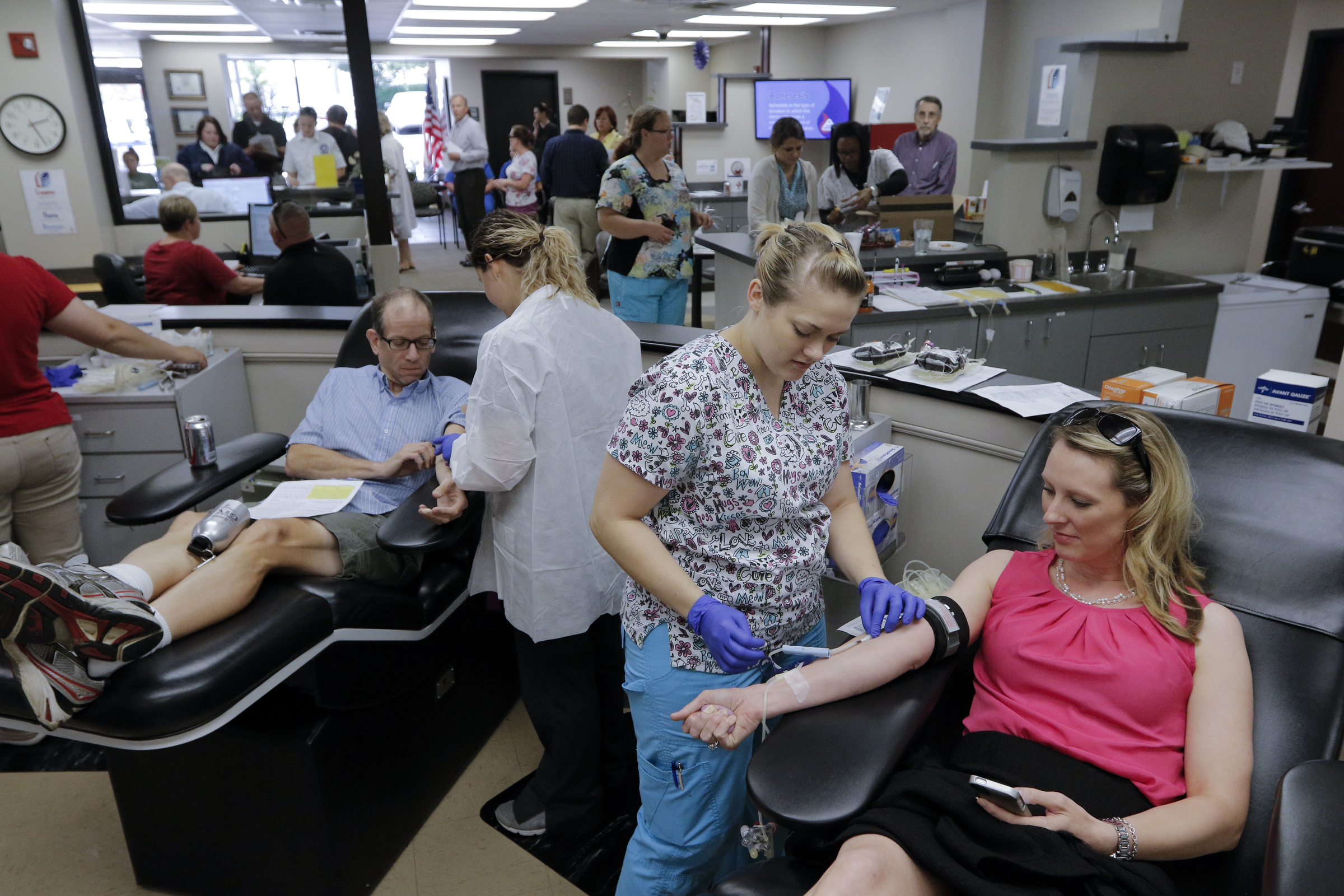 Phlebotomist Katrice Davenport, center, prepares to take donated blood from Emily Ramsey at the Blood Assurance center Thursday, July 116, 2015, in Chattanooga, Tenn. Ramsey, whose husband is a former marine who served in the local unit, came to donate after hearing about the shooting at both the Lee Highway Armed Forces Career Center and the Naval Operational Support Center on Amnicola Highway which left five dead, including the shooter, and a Chattanooga police officer wounded.