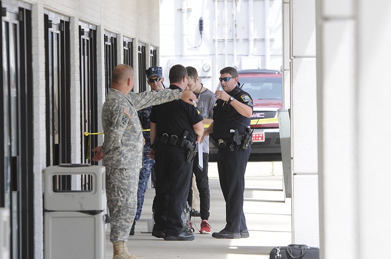 Chattanooga police talk to Reserve Recruitment Center personnel at the Lee Hwy office as the area is cordoned off with blue shell casing markers in the parking lot on Thursday, July 16, 2015 in Chattanooga.