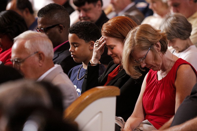 Donna Christian-Lowe puts her hand to her face as people bow their heads in prayer during an interfaith vigil at Olivet Baptist Church held in remembrance of victims of the July, 16 shootings on Friday, July 17, 2015, in Chattanooga, Tenn. The vigil was held one day after gunman Mohammad Youssef Abdulazeez shot and killed four U.S. Marines and wounded two others and a Chattanooga police officer at the Naval Operational Support Center on Amnicola Highway shortly after firing into the Armed Forces Career Center on Lee Highway.