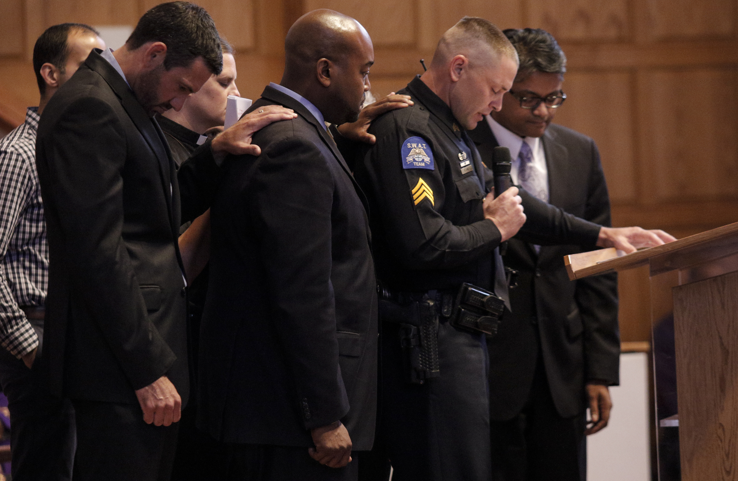 Clergy and supporters put their hands on the shoulder of Chattanooga Deputy Police Chief David Roddy as he speaks during an interfaith vigil at Olivet Baptist Church held in remembrance of victims of the July, 16 shootings on Friday, July 17, 2015, in Chattanooga, Tenn. The vigil was held one day after gunman Mohammad Youssef Abdulazeez shot and killed four U.S. Marines and wounded two others and a Chattanooga police officer at the Naval Operational Support Center on Amnicola Highway shortly after firing into the Armed Forces Career Center on Lee Highway.