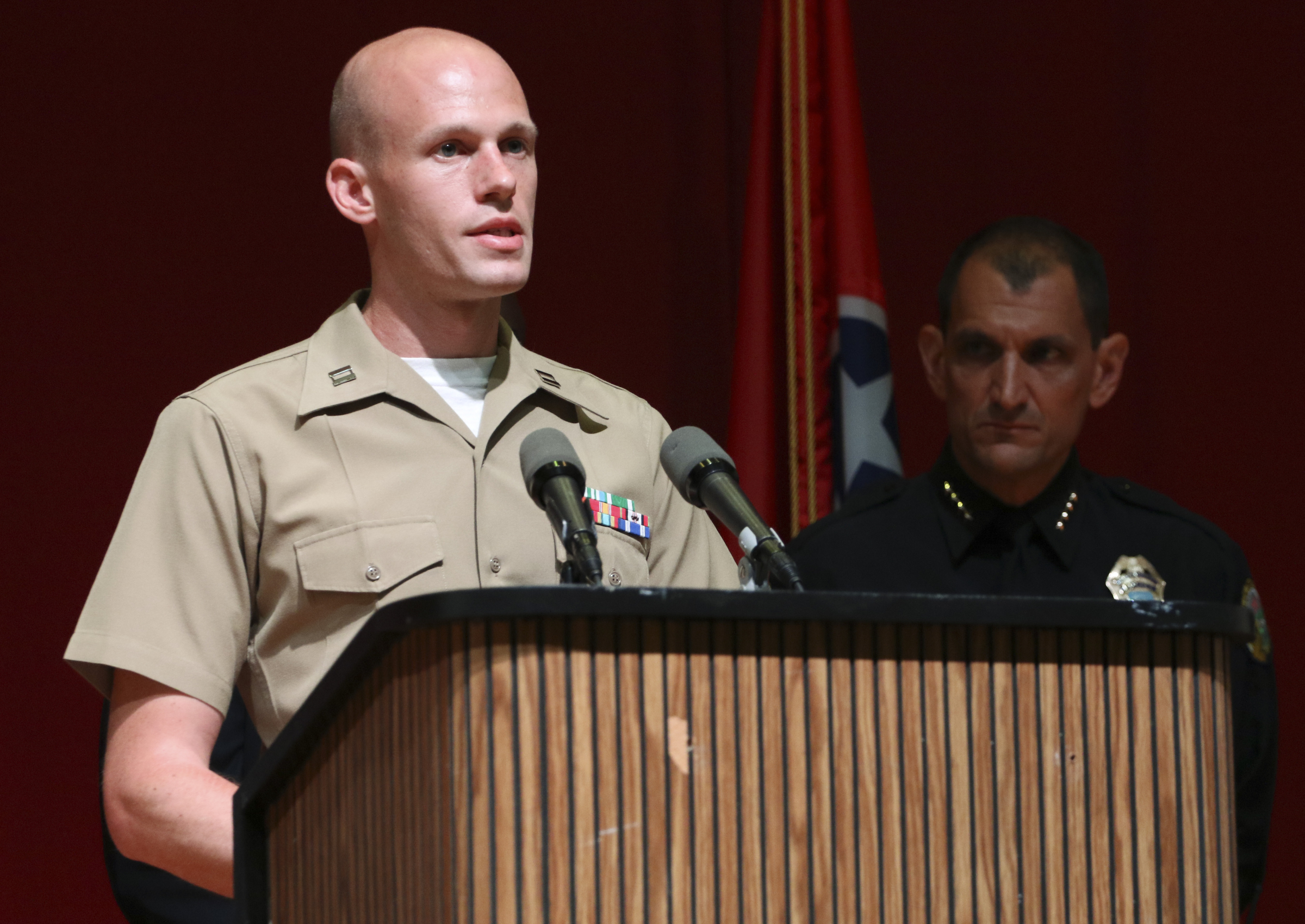 USMC Captain Ty Balzer, left, speaks to media as Chattanooga Police Chief Fred Fletcher listens from behind during a press conference at Tennessee Valley Authority's Missionary Ridge Auditorium on Friday, July 17, 2015 the day after a four Marines were shot and killed. The investigation is being treated as an act of terrorism.