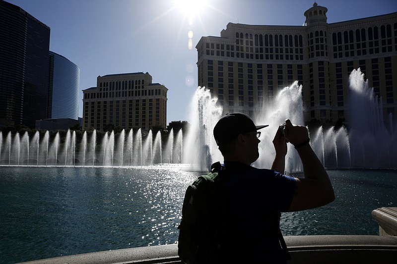 
              FILE - In this April 15, 2015 file photo, a man takes a picture of the fountains in front of the Bellagio hotel and casino in Las Vegas. The vice president of sustainability for MGM Resorts International, Chris Brophy, told a panel of the Nevada Drought Forum on Friday, July 17, the company saved 2 billion gallons of water since 2008 through a variety of conservation efforts. The company has 15 properties on the Las Vegas Strip. (AP Photo/John Locher,File)
            