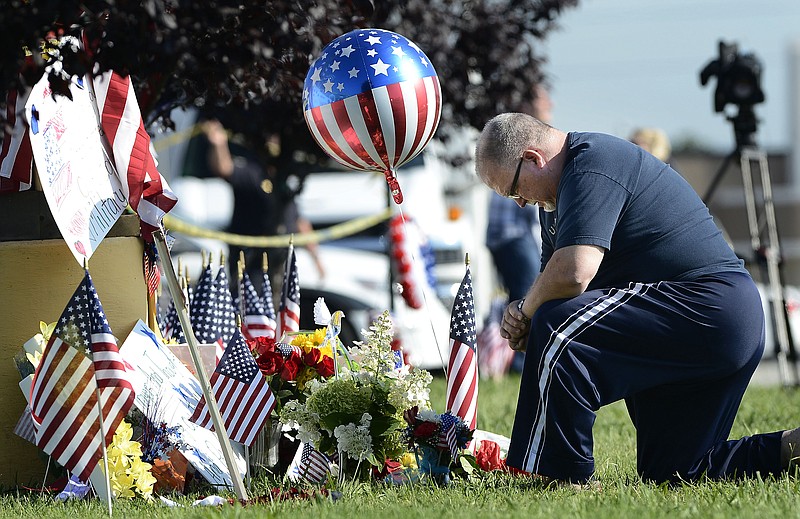 Bill Lettmkuhl kneels by a makeshift memorial in front of near the Armed Forces Career Center on Friday, July 17, 2015, in Chattanooga. Mohammad Youssef Abdulazeez attacked two military facilities on Thursday, in a shooting rampage that killed four Marines. 