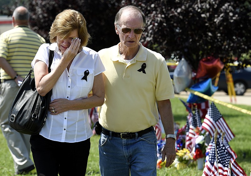 Allan Russell comforts his wife, Dee, after they visited a makeshift memorial outside the Armed Forces Career Center on Friday, July 17, 2015, in Chattanooga, Tenn. Counterterrorism investigators are trying to figure out why a 24-year-old Kuwait-born man, who by accounts lived a typical life in suburban America, attacked the career center and a Navy-Marine training center a few miles away in a shooting rampage that killed four Marines. 