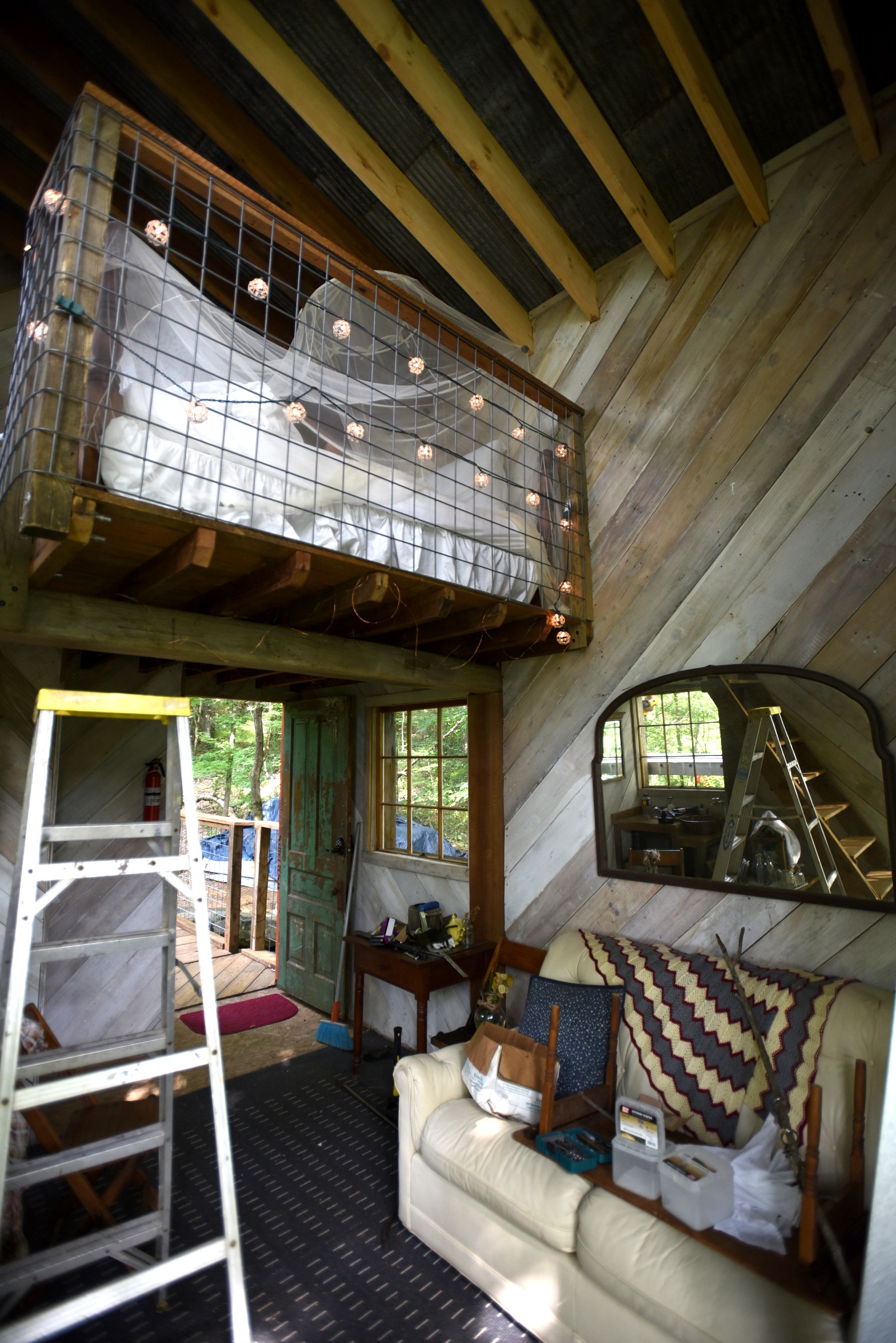The treehouse interior features a couch and a loft bed.