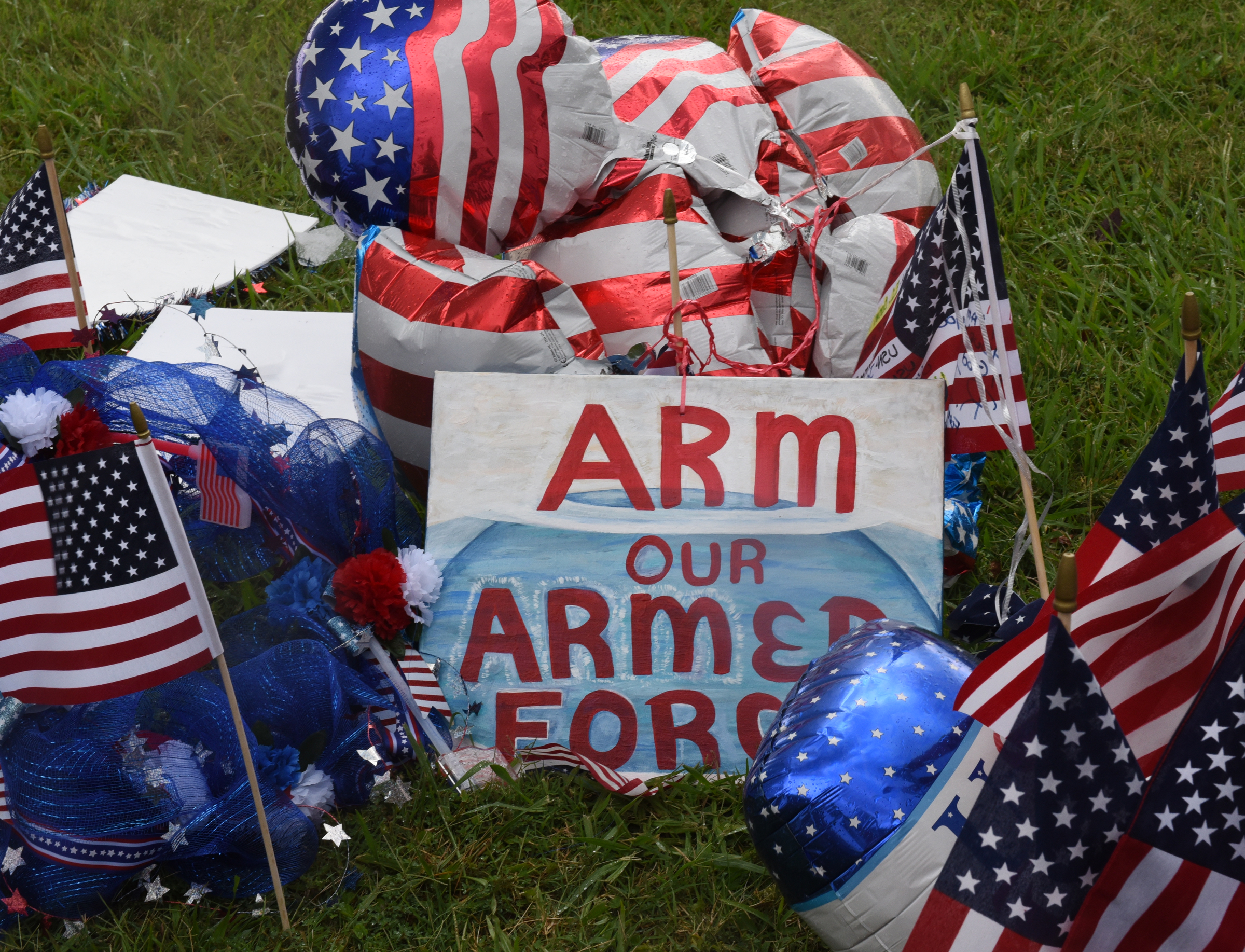 A sign the makeshift memorial at the Armed Forces Career Center on Lee Highway seen Sunday, July 19, 2015, in Chattanooga, Tenn., reads "arm our armed forces." A Thursday terrorist attack at two locations in Chattanooga killed four Marines and one member of the U.S. Navy.