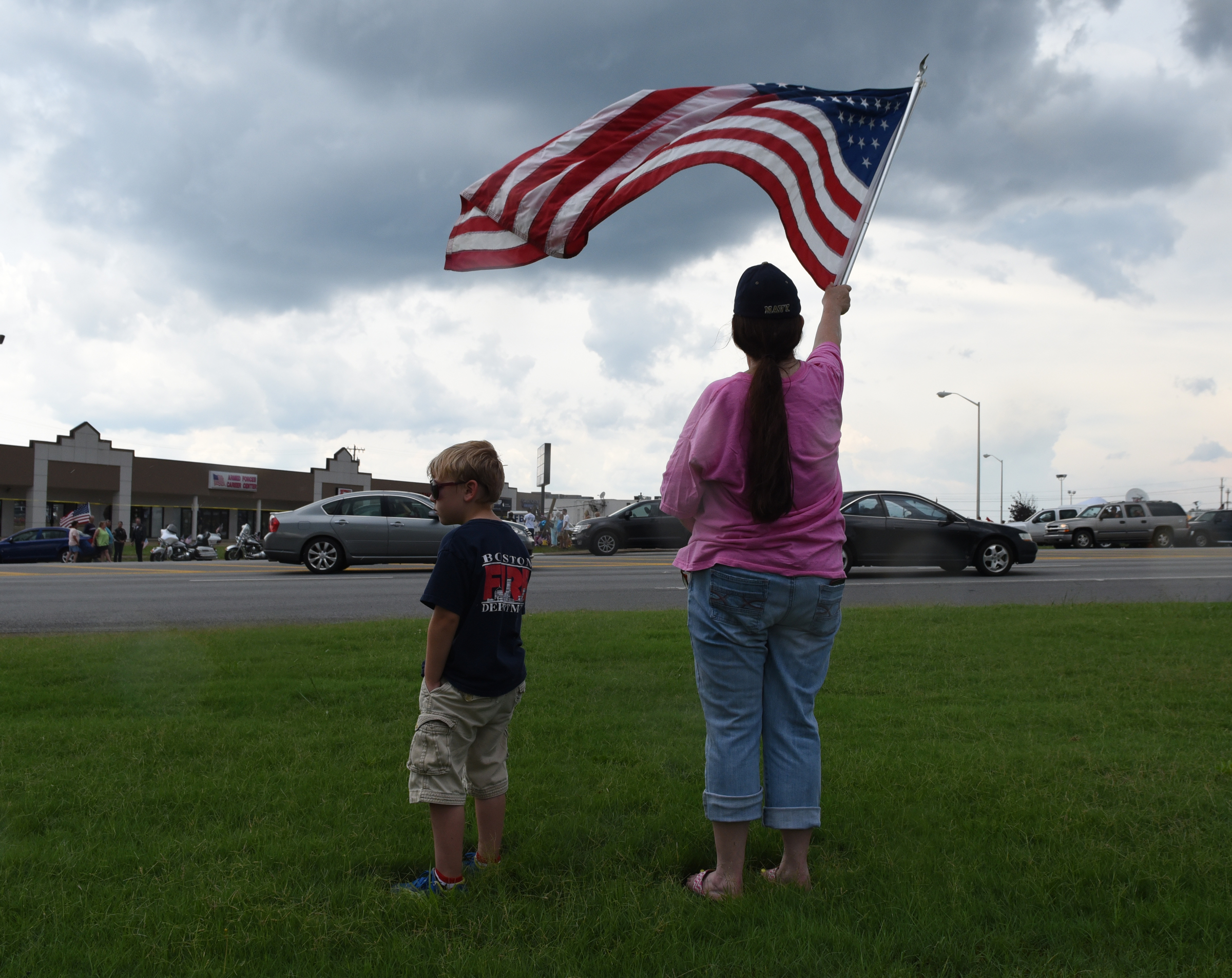 Zachary Meadows stands next to Cheryl Jenkins as she waves a flag while standing by the side of Lee Highway on Sunday, July 19, 2015, in Chattanooga, Tenn., in the aftermath of a Thursday terrorist attack that killed four Marines and one member of the U.S. Navy.