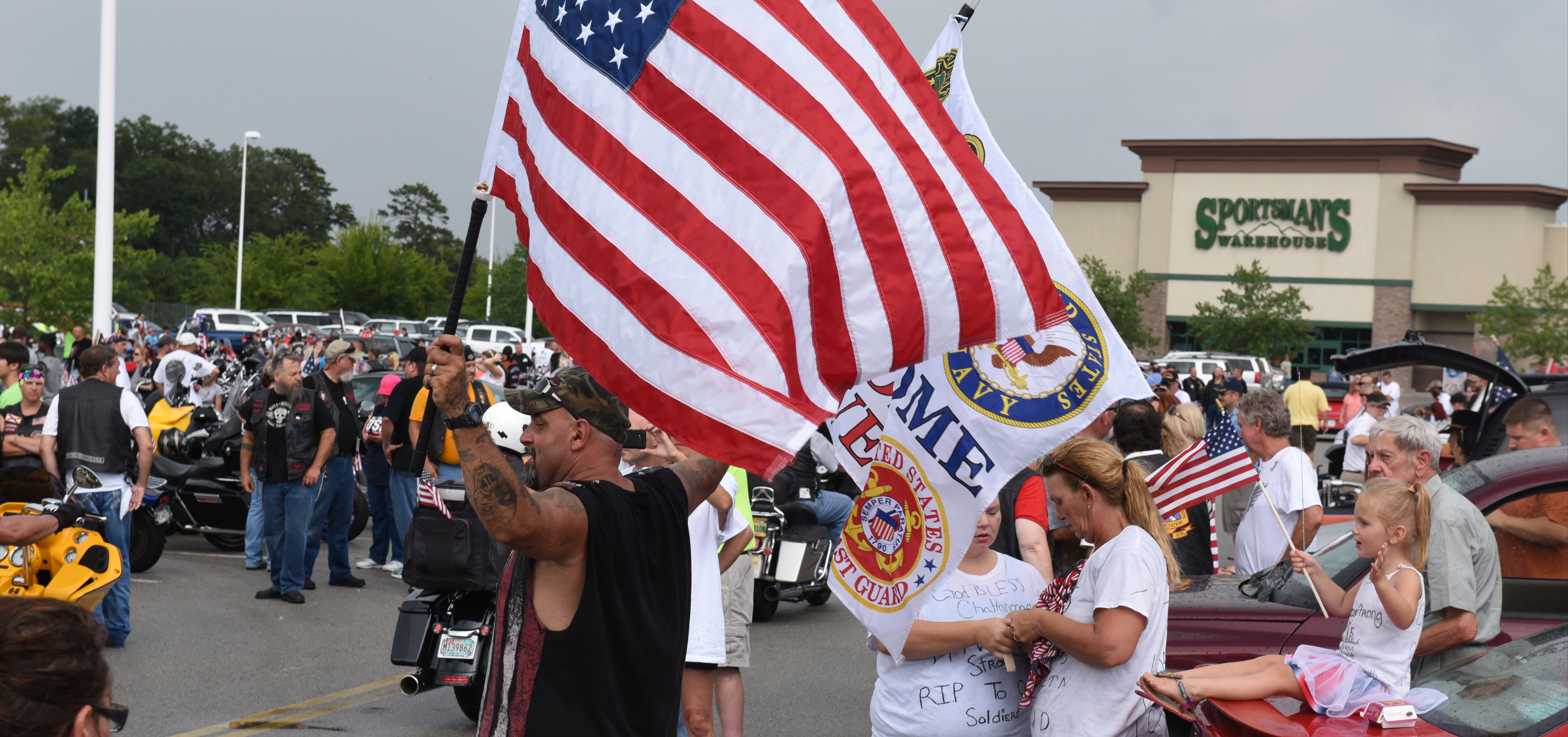 Brian Hughes waves two flags as he greets motorcycle riders gathering for a ride Sunday, July 19, 2015, in Chattanooga, Tenn., in the aftermath of a Thursday terrorist attack that killed four Marines and one member of the U.S. Navy. Hundreds of motorcyclists rode from the Armed Forces Career Center on Lee Highway to the U.S. Naval and Marine Reserve Center on Amnicola Highway. Shootings occurred at both locations.