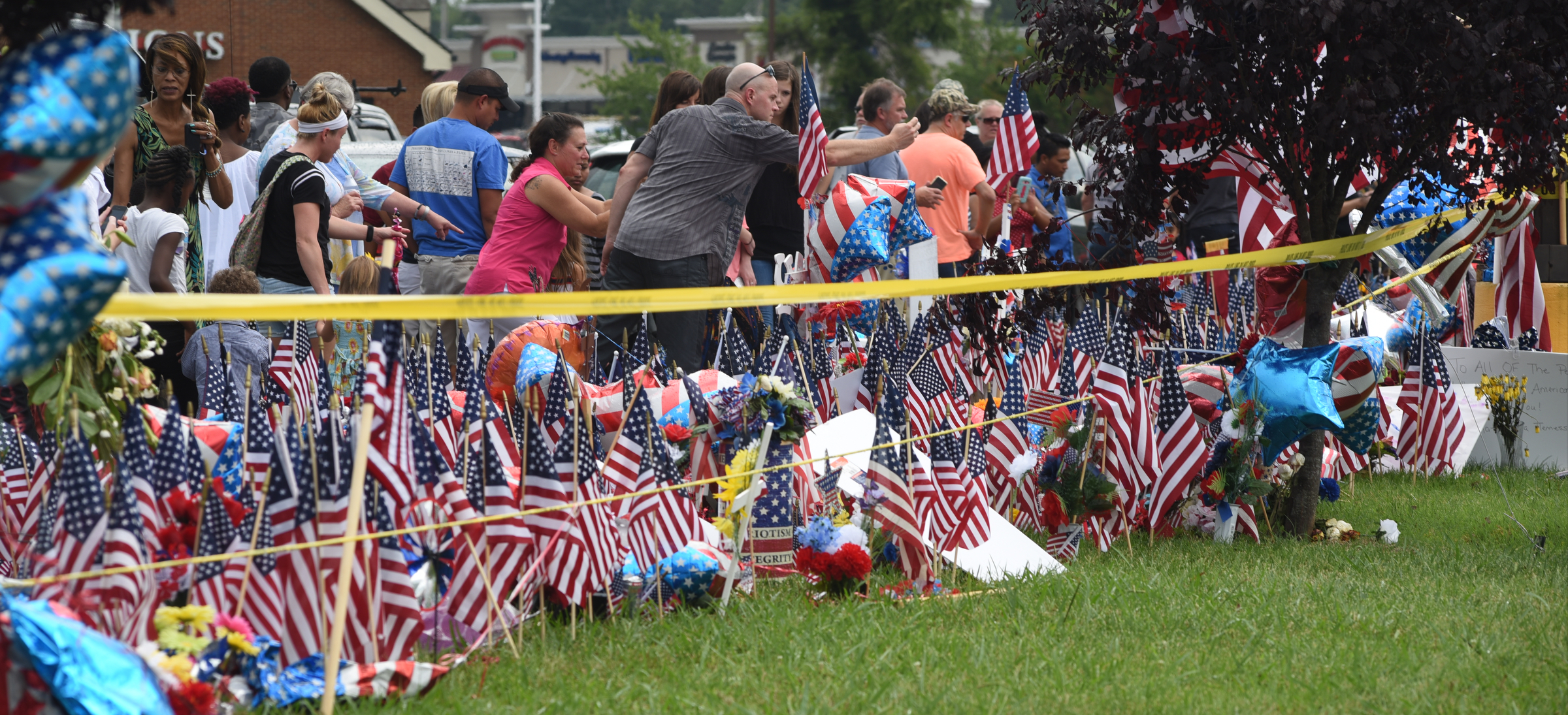 People gather at a memorial in front of the Armed Forces Career Center on Lee Highway on Sunday, July 19, 2015, in Chattanooga, Tenn., in the aftermath of a Thursday terrorist attack that killed four Marines and one member of the U.S. Navy.
