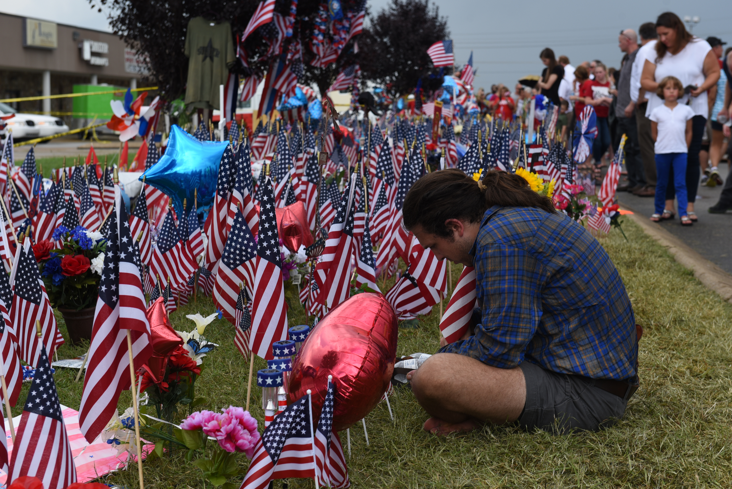 John David Whitehead, from Knoxville, sits at the makeshift memorial at the Armed Forces Career Center on Lee Highway on Sunday, July 19, 2015, in Chattanooga, Tenn. A Thursday terrorist attack at two locations in Chattanooga killed four Marines and one member of the U.S. Navy.