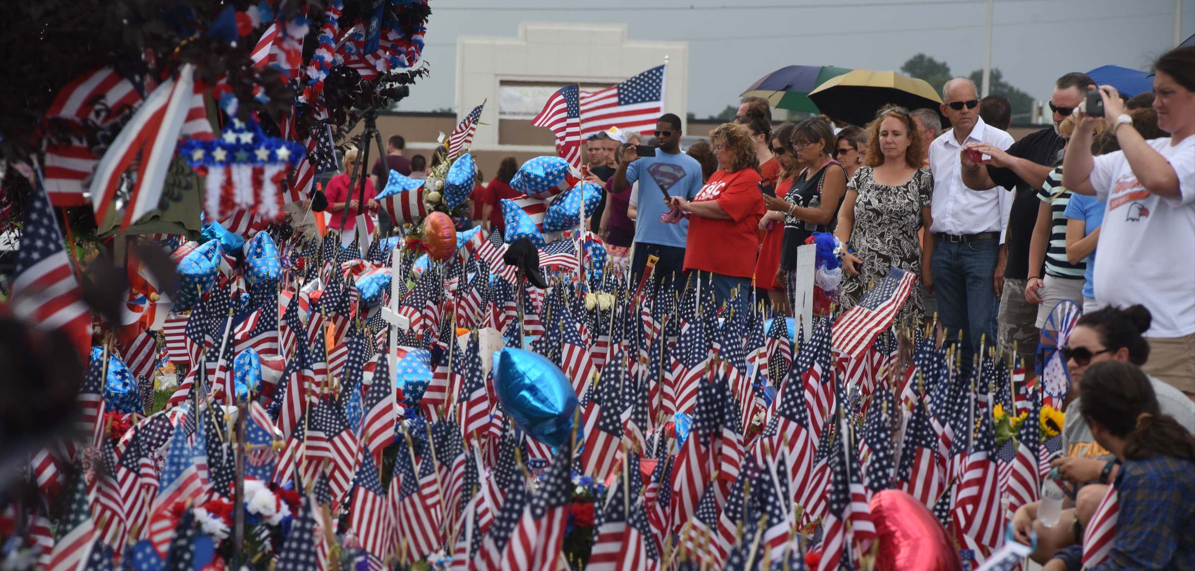People gather at a memorial in front of the Armed Forces Career Center on Lee Highway on Sunday, July 19, 2015, in Chattanooga, Tenn., in the aftermath of a Thursday terrorist attack that killed four Marines and one member of the U.S. Navy.