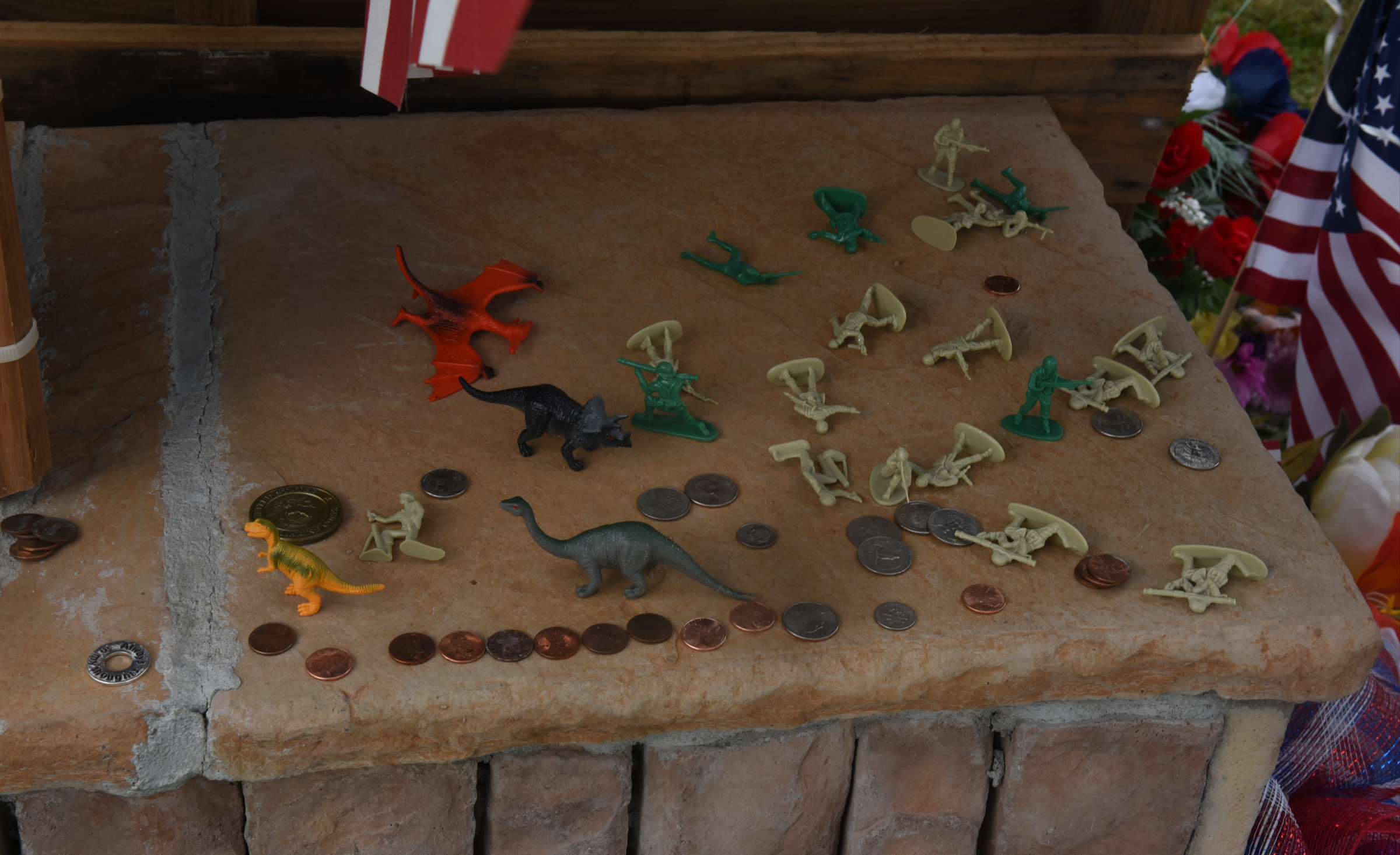 Toy soldiers, plastic dinosaurs and coins are seen placed on the makeshift memorial at the Armed Forces Career Center on Lee Highway on Sunday, July 19, 2015, in Chattanooga, Tenn. A Thursday terrorist attack at two locations in Chattanooga killed four Marines and one member of the U.S. Navy.