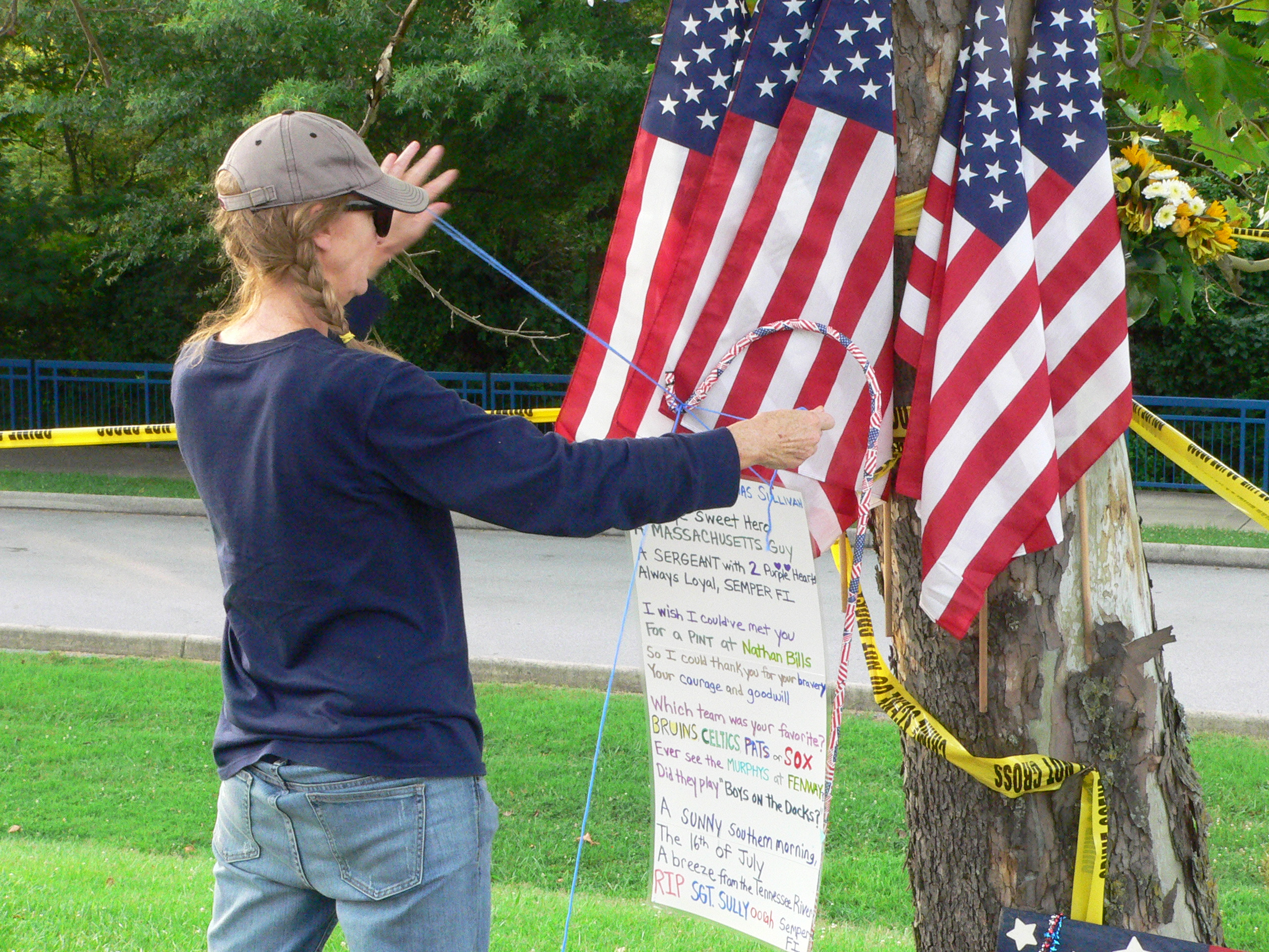A woman installs a memorial poster for Sgt. Sullivan at the impromptu memorial on Amnicola Highway in front of the Navy/Marine operations center.