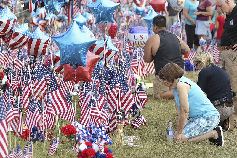 Charlene Jacobs, right, kneels to pay her respects Monday while at the Lee Highway memorial set up for last Thursday's Chattanooga shooting victims.