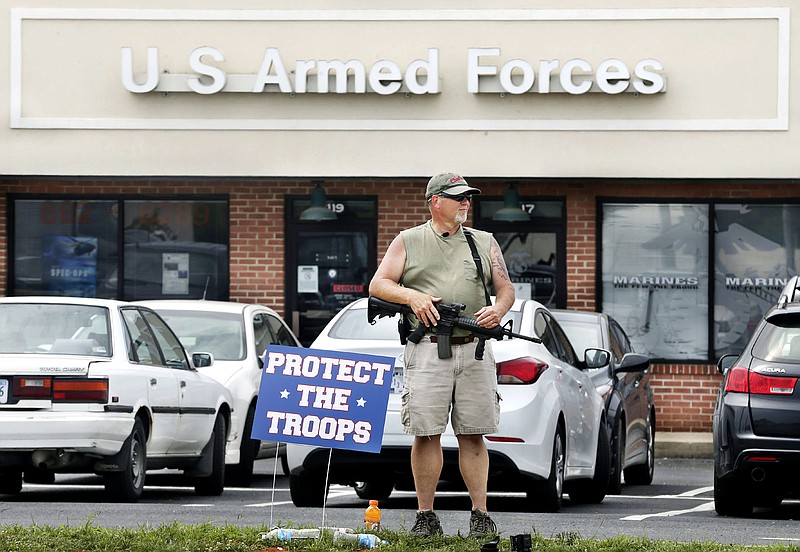 A man holding a rifle stands in front of the armed forces recruiting center in Winchester, Va., Friday, July 17, 2015. The man stated that he was there "to protect the troops." Security at military recruiting and reserve centers will be reviewed in the aftermath of a deadly shooting in Tennessee. (Scott Mason/The Winchester Star via AP) 