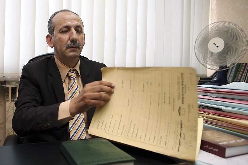 Abed al-Kader Ahmad al-Khateeb, a lawyer of Asaad Ibrahim Asaad Haj Ali, an uncle of the Chattanooga attacker, Muhammad Youssef Abdulazeez, goes over paper during an interview with The Associated Press in Amman, Jordan, on Tuesday. The uncle of Abdulazeez, who killed four Marines and a sailor in attacks on Tennessee military sites last week, has been in custody in Jordan since a day after the attack, the lawyer said. He also said he was barred from seeing his client and that family members were also prevented from visiting the detainee. (AP Photo/Raad Adayleh)