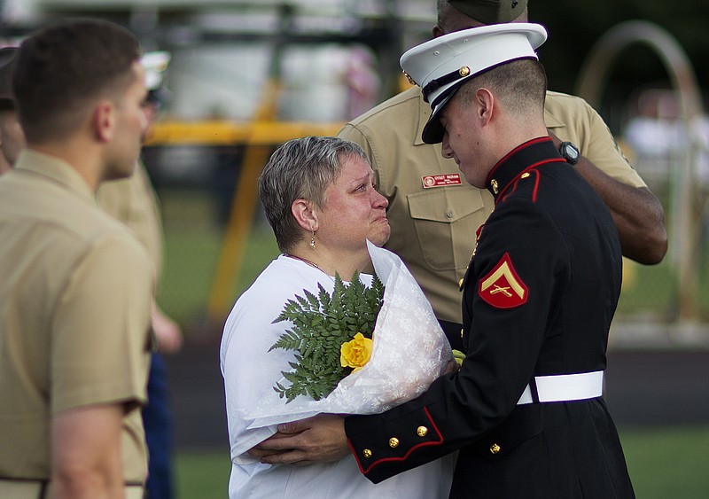 Cathy Wells, left, the mother of Lance Cpl. Squire "Skip" Wells, is embraced by Lance Cpl. Kurt Bright, one of Wells' best friends, upon arriving for a memorial service for her son at Sprayberry High School where he attended.